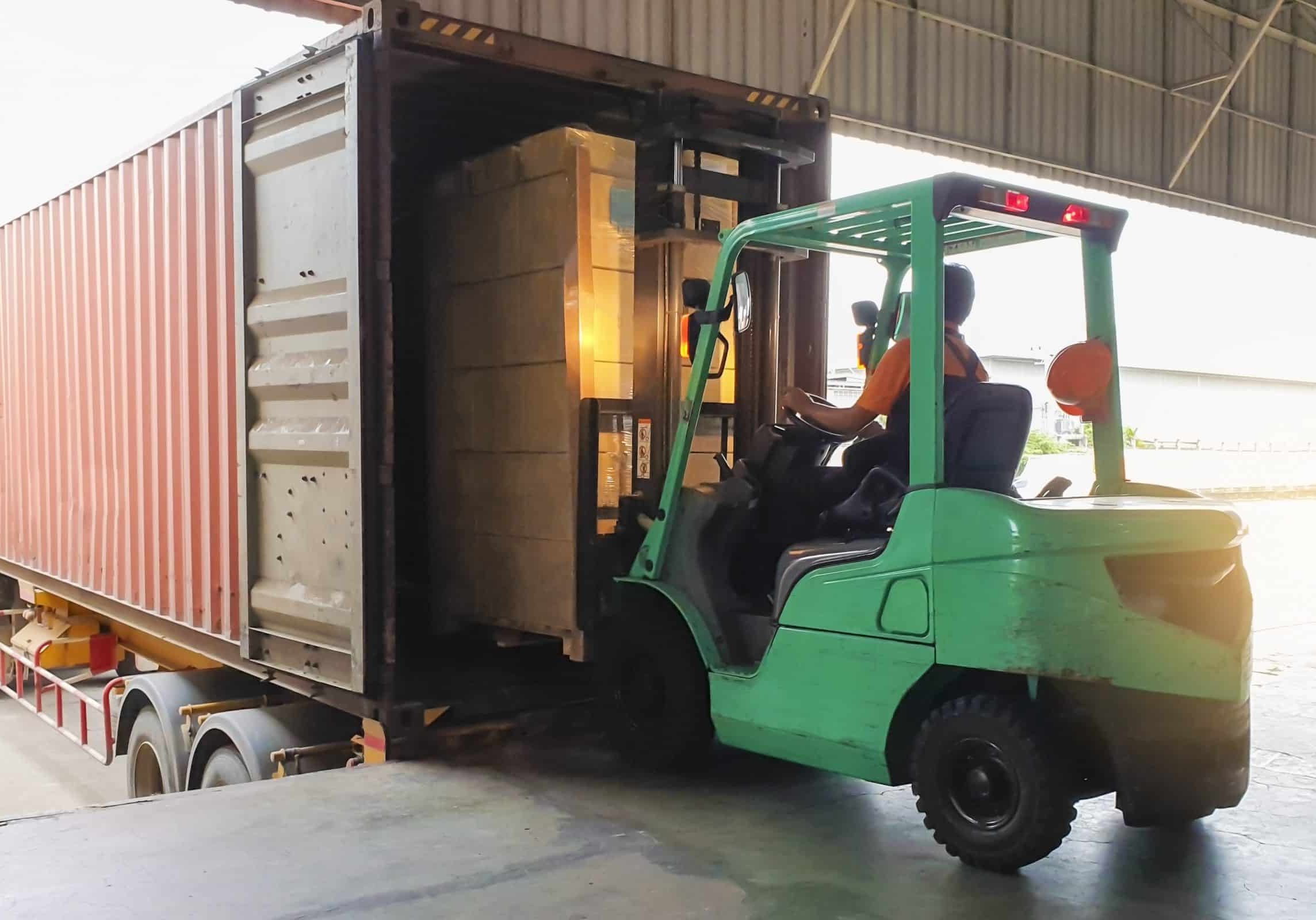 Forklift driver loading goods pallet into the truck container, freight industry warehouse logistics and transport pallet network