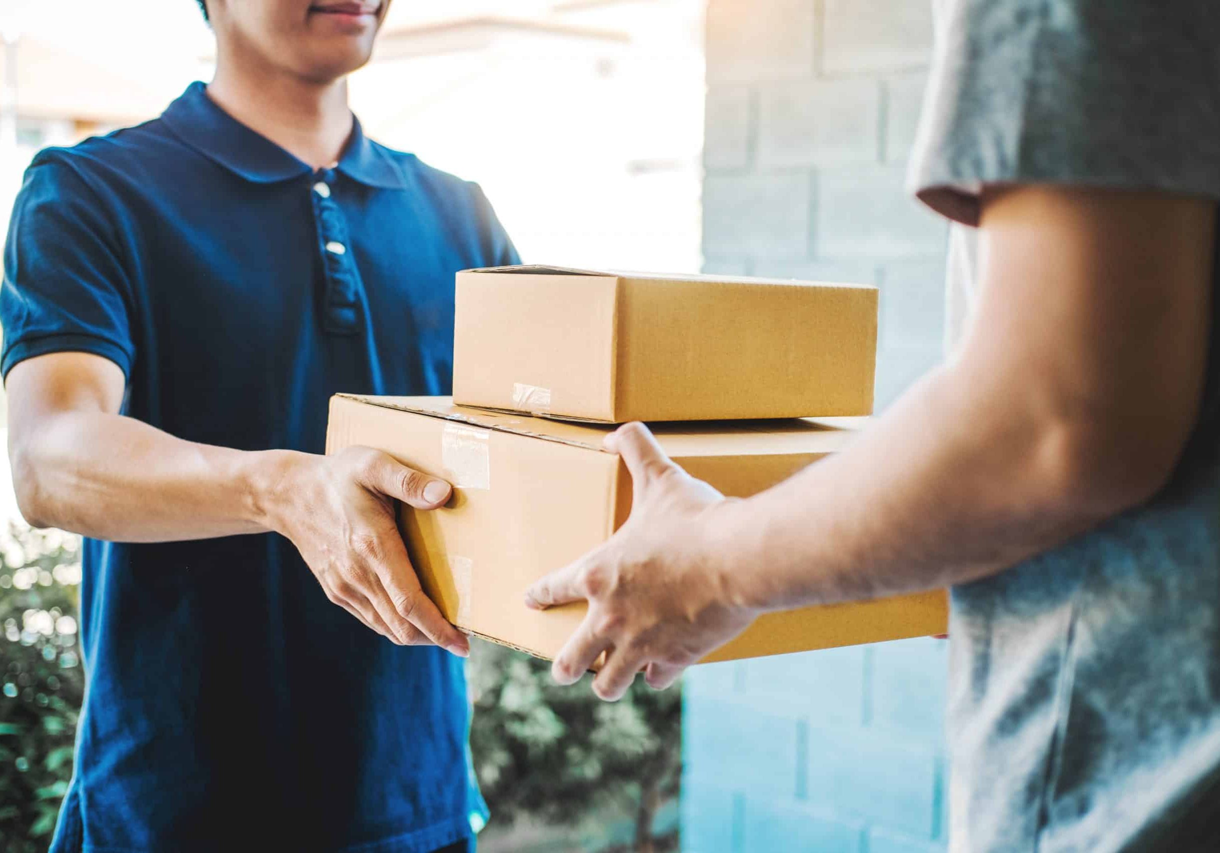 Delivery concept Asian Man hand accepting a delivery boxes from professional deliveryman at home Deliverymen delivering goods to clients